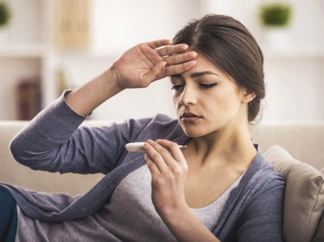 Girl holding her head and checking her temperature