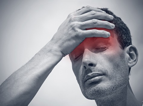 Man suffering from migraine holding his head 